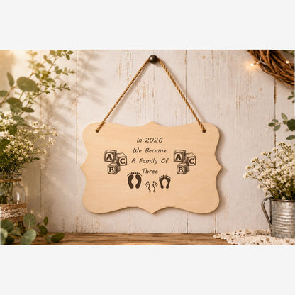 In 2026 We Became a Family of 3 plaque displayed in a family home setting