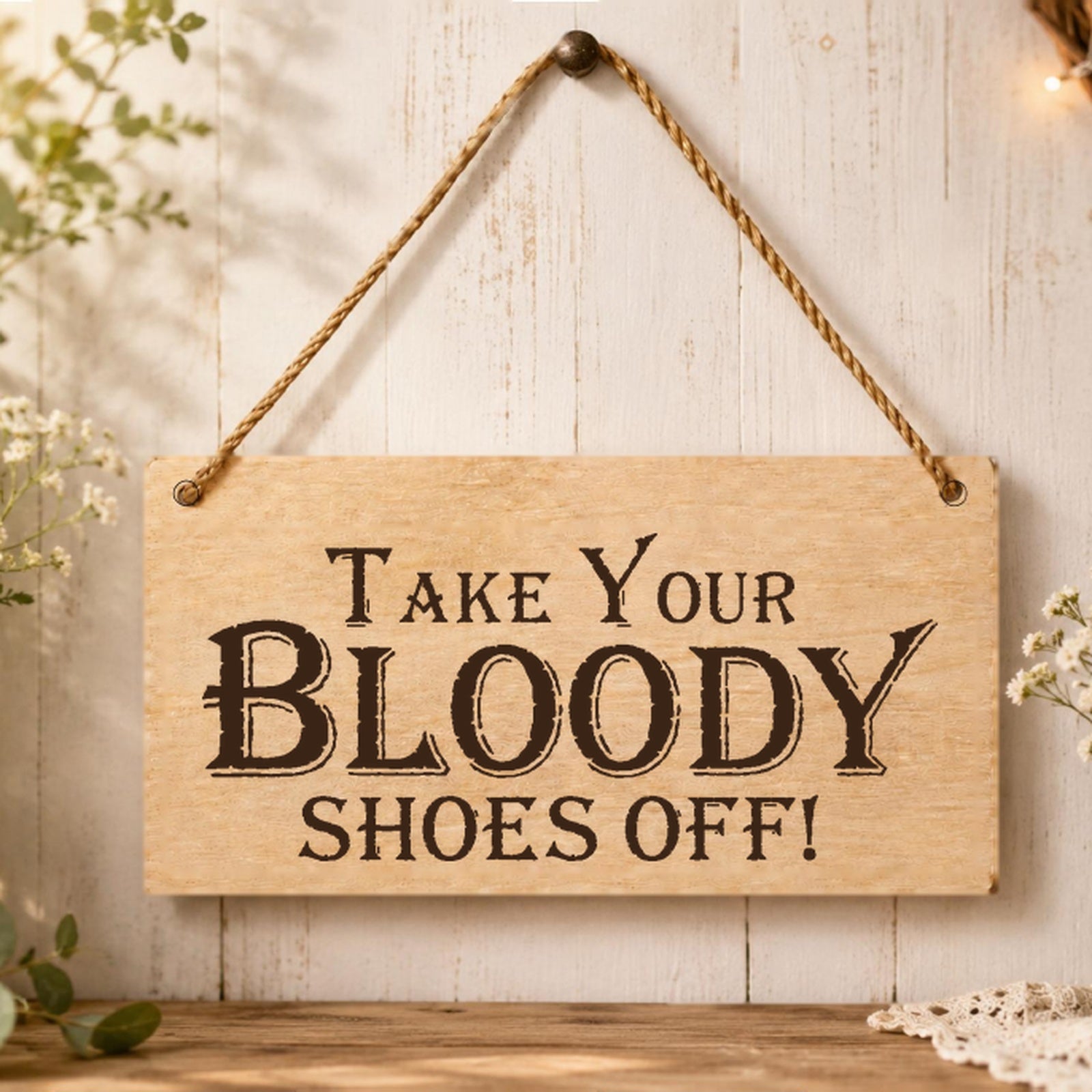 Take Your Bloody Shoes Off plaque displayed in a hallway setting